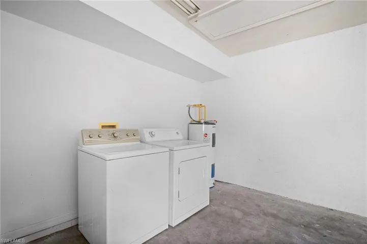 Washroom featuring concrete floors, washer and dryer, and electric water heater