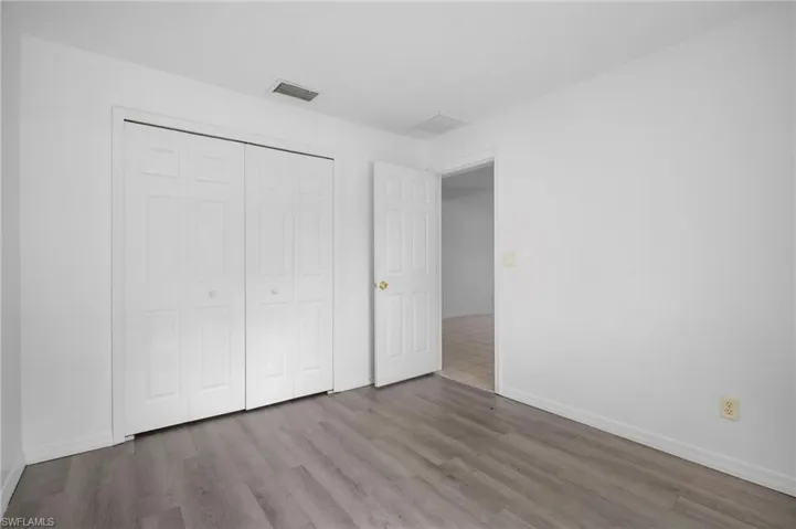 Unfurnished bedroom with wood finished floors and a closet