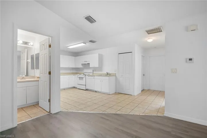 Kitchen featuring light wood-style floors, white cabinets, light countertops, white appliances, and under cabinet range hood