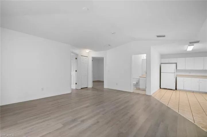Unfurnished living room featuring vaulted ceiling and light wood-type flooring