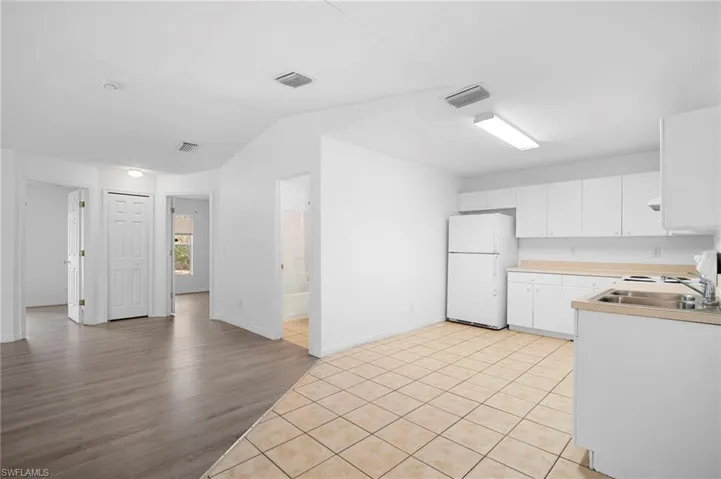 Kitchen with freestanding refrigerator, white cabinetry, light countertops, light wood-style flooring, and range