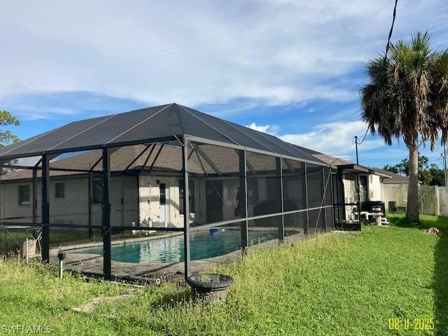Back of property featuring a sunroom, an outdoor pool, a patio area, and glass enclosure