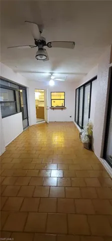 Unfurnished living room with ceiling fan and a textured wall