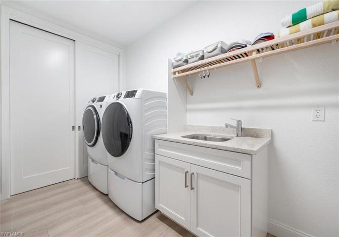Full size front loading washer/dryer with tub sink and granite counter top.
