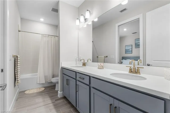 Full bathroom featuring a double vanity with gray cabinetry, white countertops, and dual undermount sinks