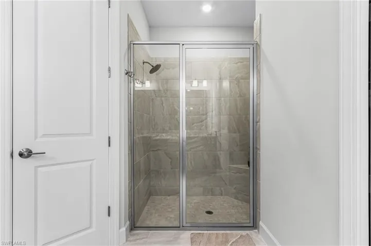 Glass-enclosed shower with a tiled surround, built-in bench, and rainfall showerhead