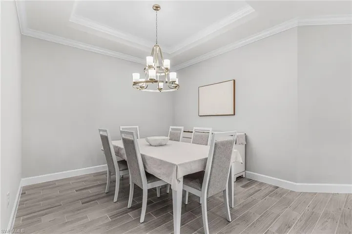 Dining area with tray ceiling, crown molding, and wood-finish flooring