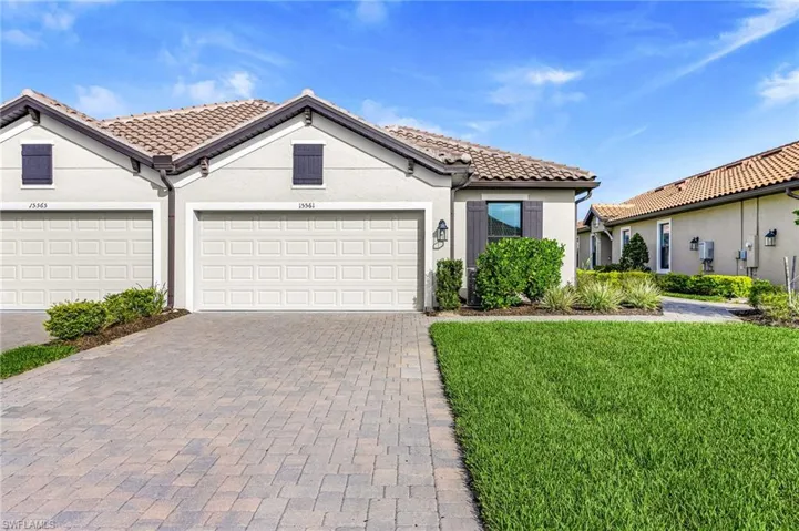 Single-story residence featuring a tile roof, stucco exterior, and a paver driveway