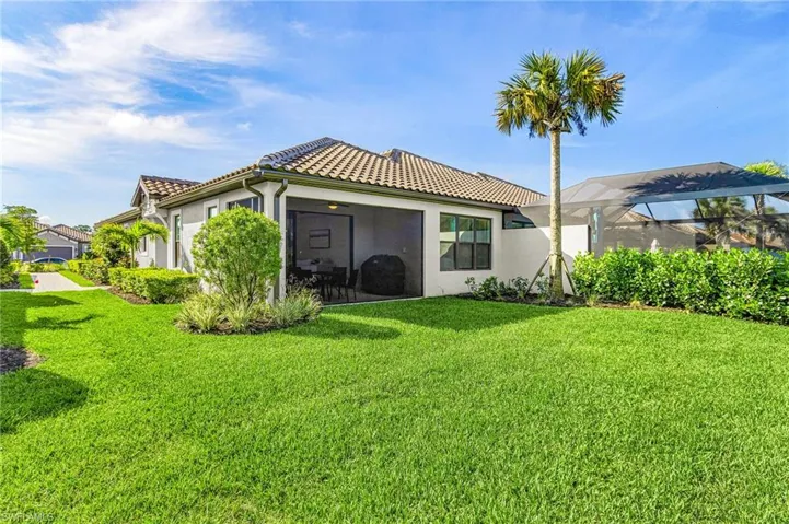 Expansive rear yard featuring a manicured lawn, screened patio, and mature landscaping