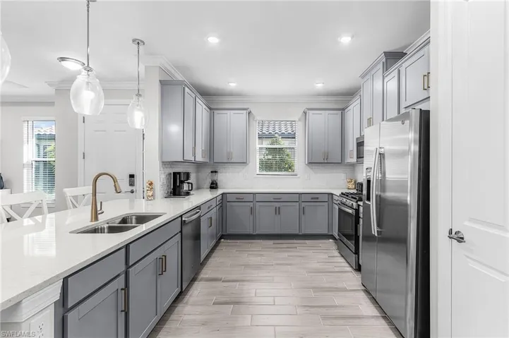 Contemporary kitchen featuring light gray cabinetry, stainless steel appliances, light-toned countertops, a white subway tile backsplash, and light wood-finish flooring