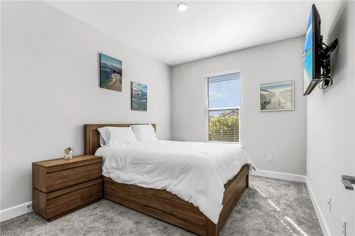 Bedroom featuring light grey walls, grey carpet, and a window with horizontal blinds