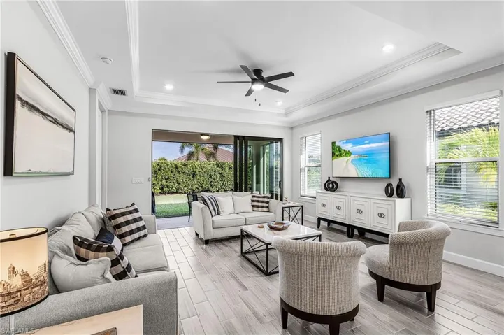 Spacious interior with wood-finish tile flooring, recessed lighting, and a tray ceiling with crown molding