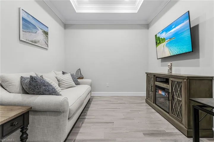 Recessed ceiling with crown molding, light wood-finish flooring, and light gray wall paint