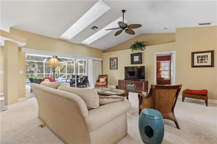 Living room featuring ceiling fan, carpet floors, and vaulted ceiling with skylight
