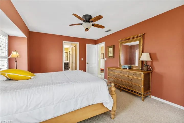 Carpeted bedroom featuring ceiling fan and ensuite bathroom