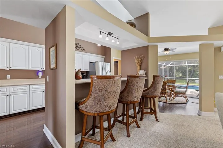 Kitchen featuring stainless steel refrigerator, ceiling fan, dark hardwood / wood-style floors, a breakfast bar area, and white cabinets