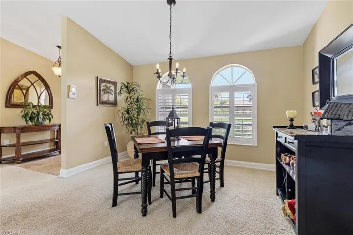 Dining area with lofted ceiling, carpet, and a chandelier