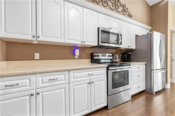 Kitchen with white cabinetry, stainless steel appliances, and dark hardwood / wood-style floors