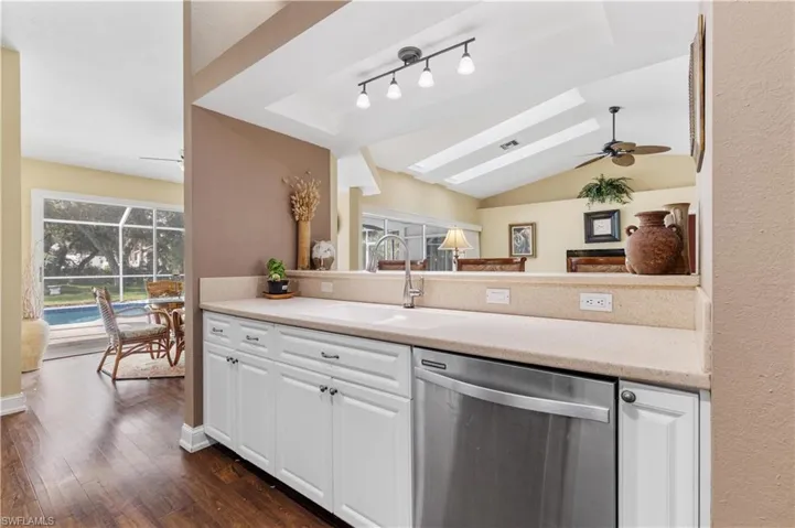 Kitchen featuring stainless steel dishwasher, dark wood-type flooring, sink, white cabinetry, and ceiling fan