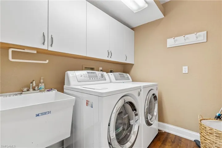 Clothes washing area with dark hardwood / wood-style floors, cabinets, sink, and independent washer and dryer