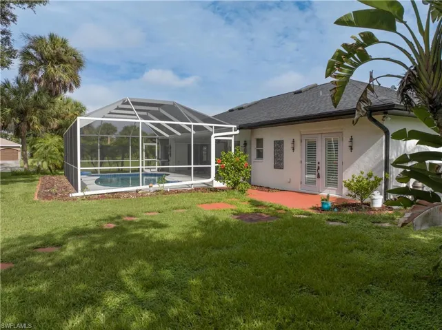 Back of property with a lawn, a patio, and glass enclosure