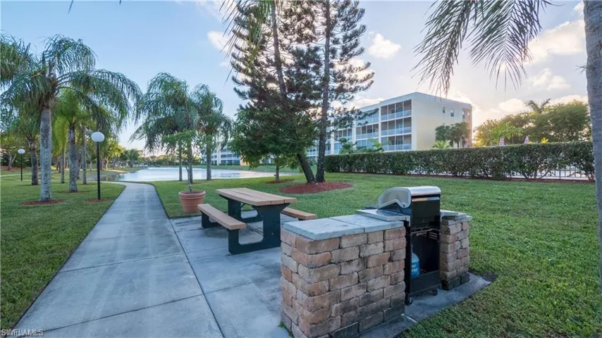 View of home's community with a lawn, picnic table, and grill.