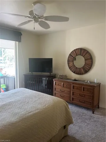 Bedroom with ceiling fan and carpet floors, lovely view out to the back yard.