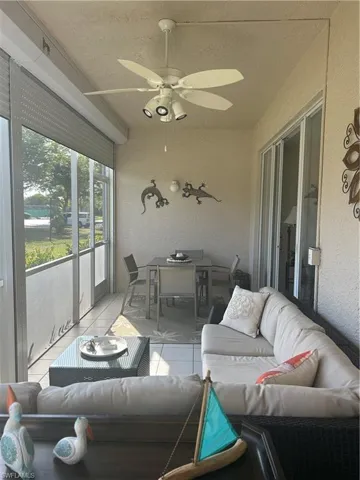 Lanai featuring outdoor lounge area, a textured wall, outdoor dining area, tile patterned flooring, and ceiling fan.  Electric Shutters