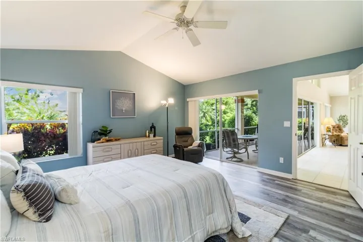 Primary Bedroom featuring vinyl plank floors, lofted ceiling, ceiling fan, and access to exterior