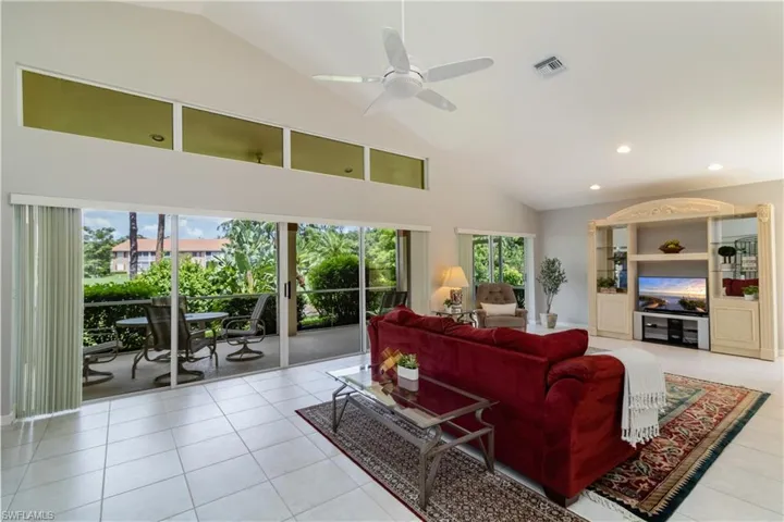 Tiled living room featuring a healthy amount of sunlight, high vaulted ceiling, and ceiling fan