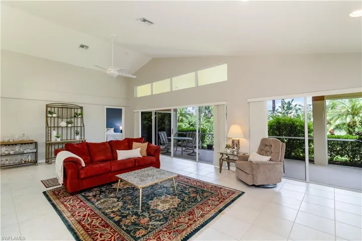 Living room with light tile flooring, ceiling fan, and high vaulted ceiling