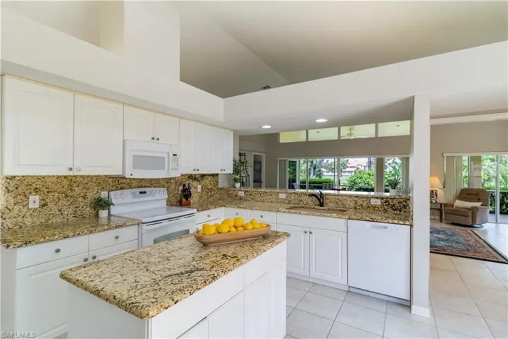 Kitchen with plenty of natural light, high vaulted ceiling, sink, and white appliances