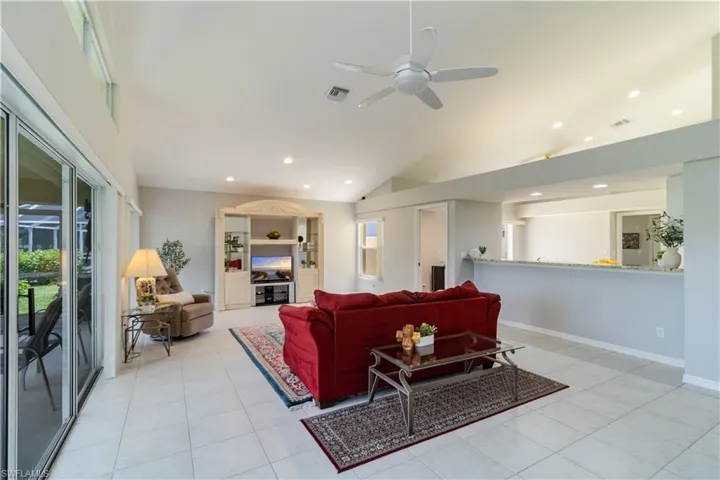 Living room featuring ceiling fan, vaulted ceiling, and light tile floors