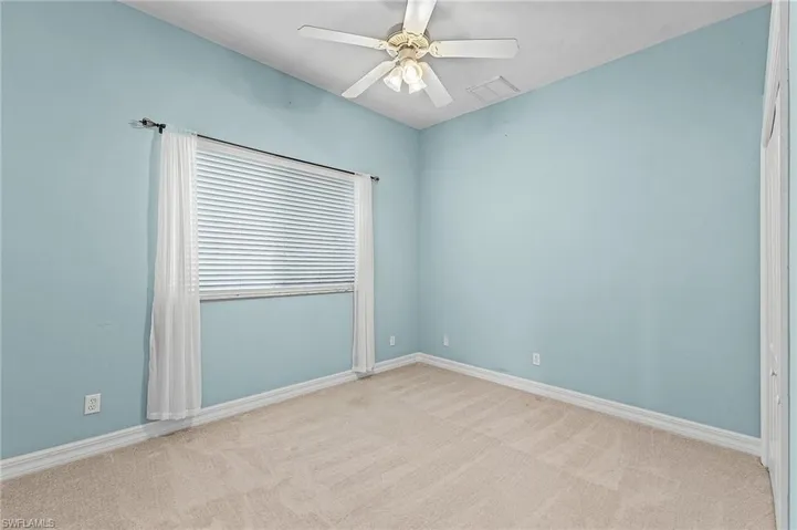 Empty room with ceiling fan and light colored carpet