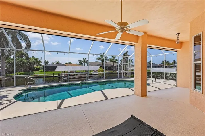 View of swimming pool with ceiling fan, a patio, and a lanai