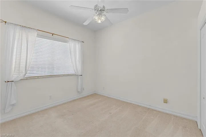 Carpeted empty room featuring ceiling fan