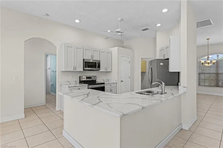 Kitchen featuring quartz countertops, newer  appliances with stainless steel finishes, light stone counters, light tile patterned floors, and sink