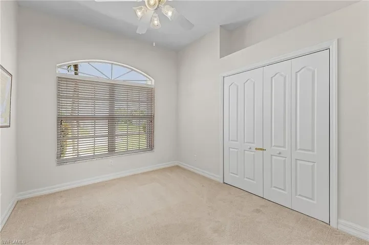 Den or 4th bedroom with light colored carpet, a closet, multiple windows, and ceiling fan