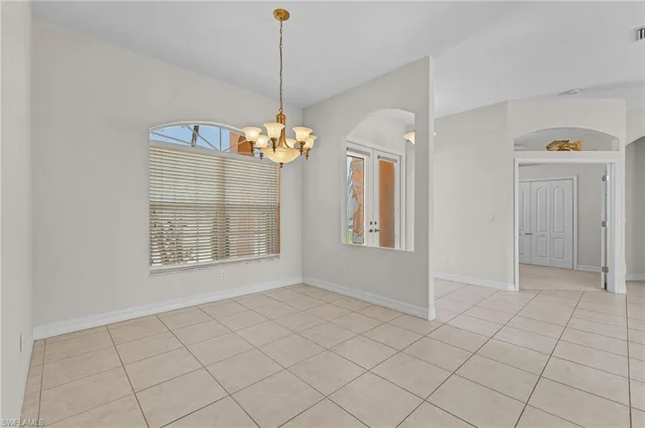 light tile patterned floors, an inviting chandelier, and a healthy amount of sunlight