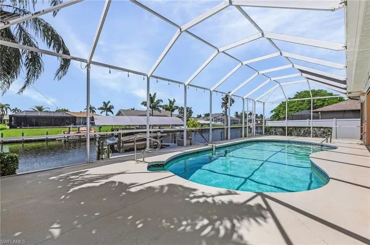 View of pool featuring glass enclosure, a water view, and a patio area