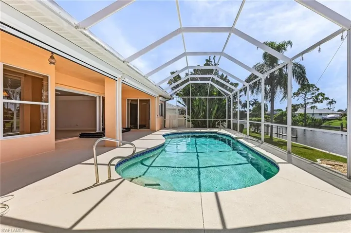 View of swimming pool featuring glass enclosure and a patio