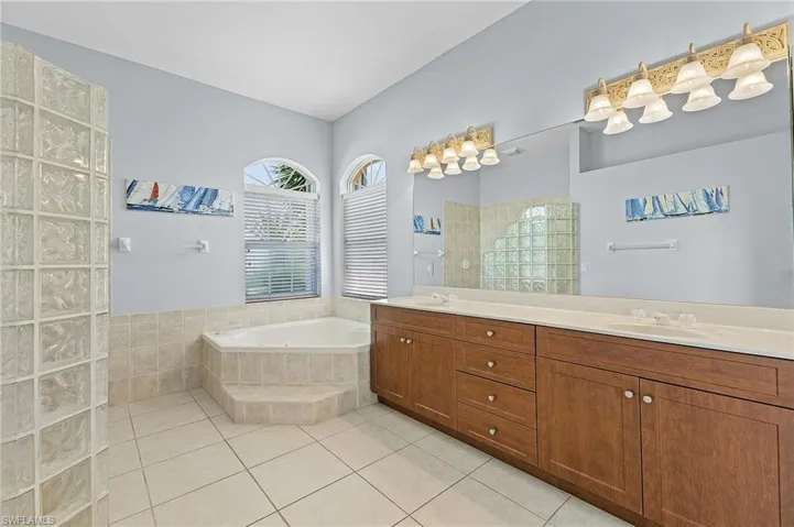 Bathroom featuring tiled bath, double sink vanity, and tile patterned floors