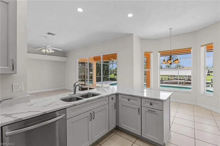 Kitchen featuring kitchen peninsula, ceiling fan, light tile patterned flooring, and stainless steel dishwasher