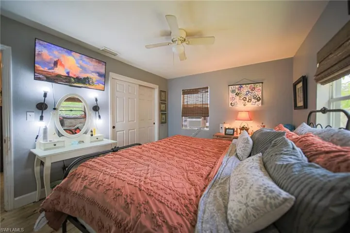 Bedroom featuring a ceiling fan, dual sliding closet doors, and wood-finish flooring