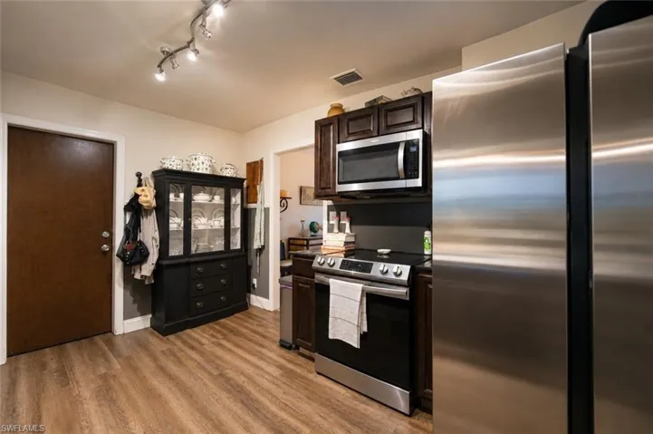 Kitchen featuring stainless steel appliances, dark wood cabinetry, and wood-finish flooring
