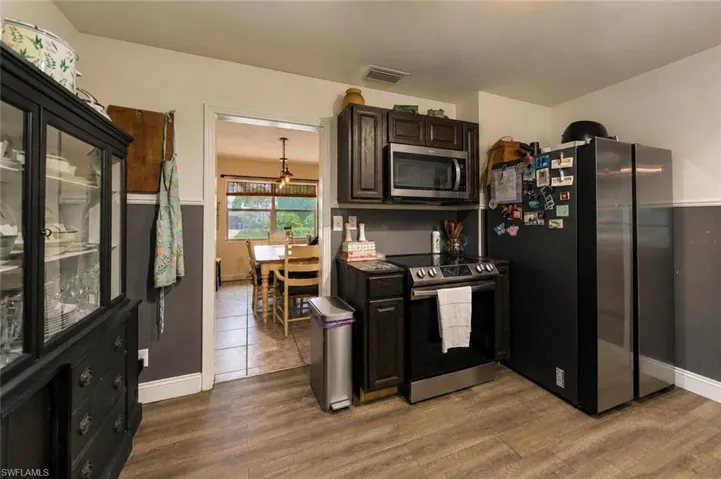 Kitchen featuring wood-finish flooring, dark wood cabinetry, a stainless steel electric range, and a stainless steel microwave