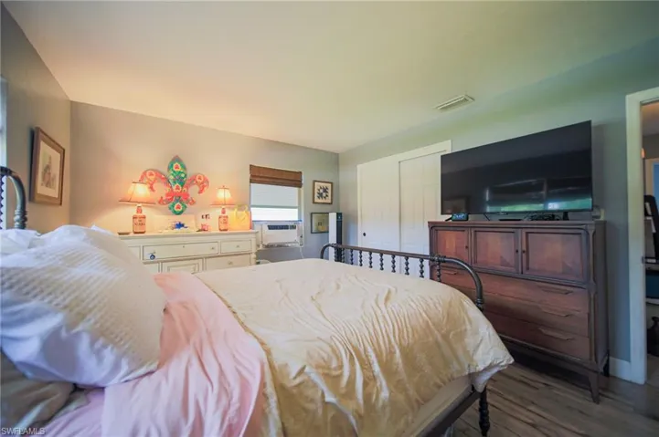Spacious room featuring wood-finish flooring, a window with blinds, and white bi-fold closet doors