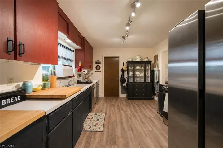 Kitchen featuring wood-finish flooring, upper red cabinetry, lower black cabinetry, and light countertops
