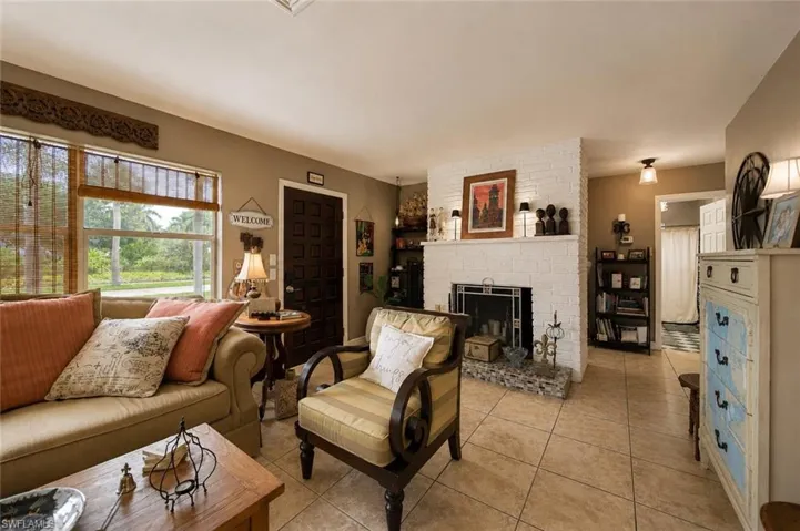 Living area featuring tile flooring, a white brick fireplace with a mosaic tile hearth, and a paneled entry door