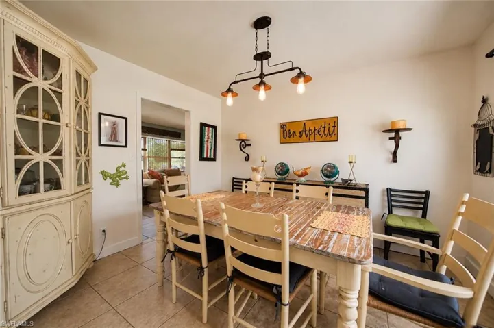 Spacious dining area featuring neutral wall tones, tile flooring, and a decorative exposed bulb light fixture
